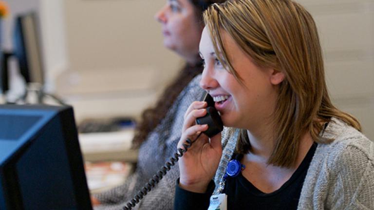 An adult woman at a medical clinic answering the phone
